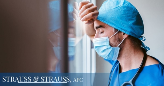 Stressed male doctor with his hand against a window